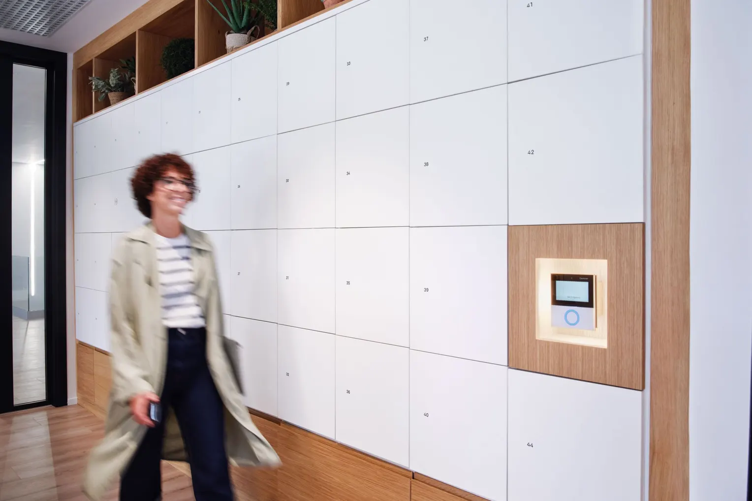 A member walks past the smart lockers beside the wall-mounted access terminal