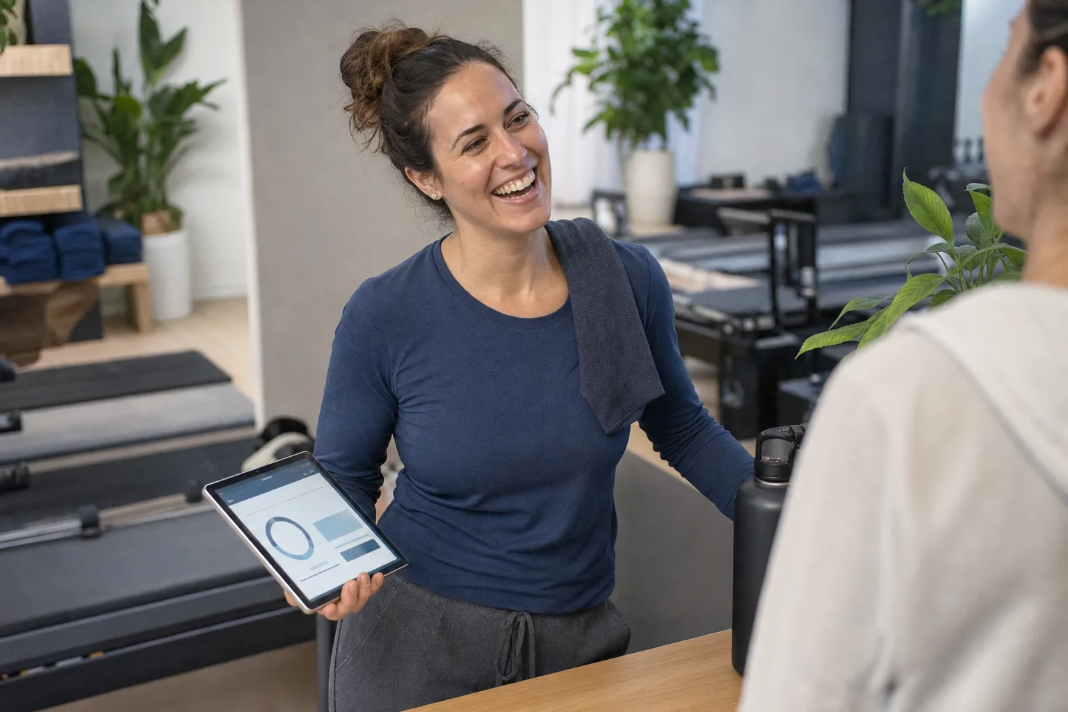 A smiling gym studio owner reviews her live numbers on a tablet.