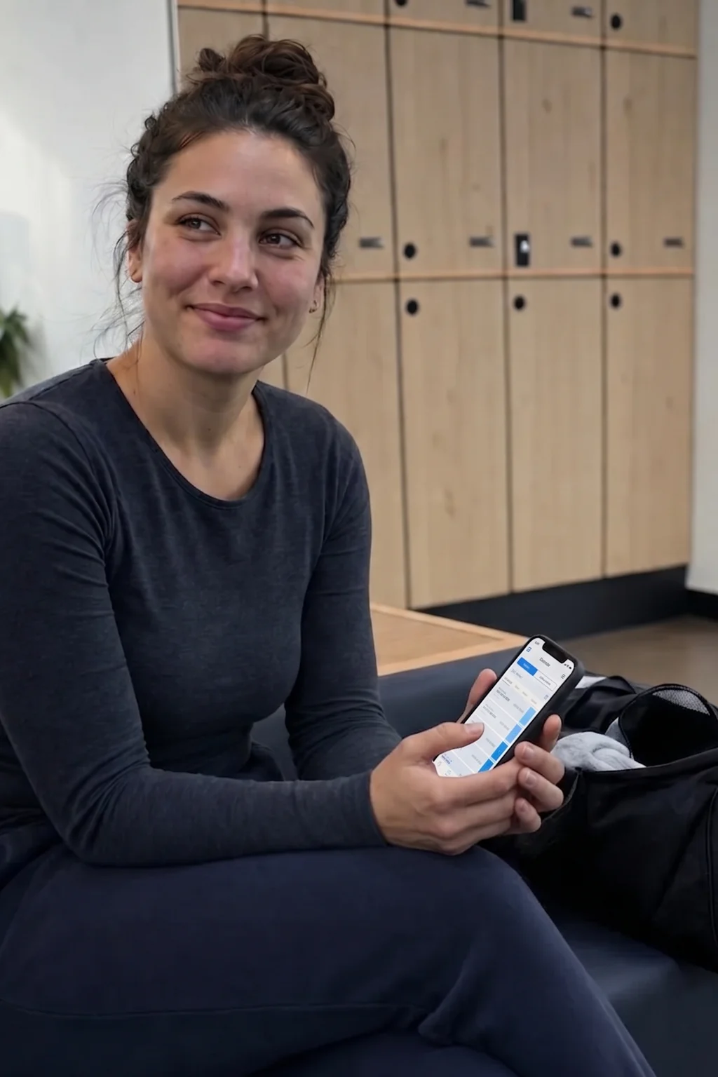 A member checks the gym's branded app on her phone in the lounge.